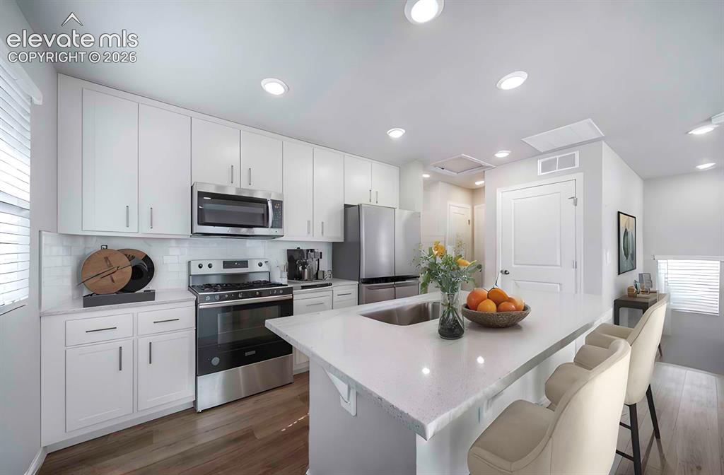 Image 12 of 18: Kitchen featuring an expansive island with an undermount sink, white cabine