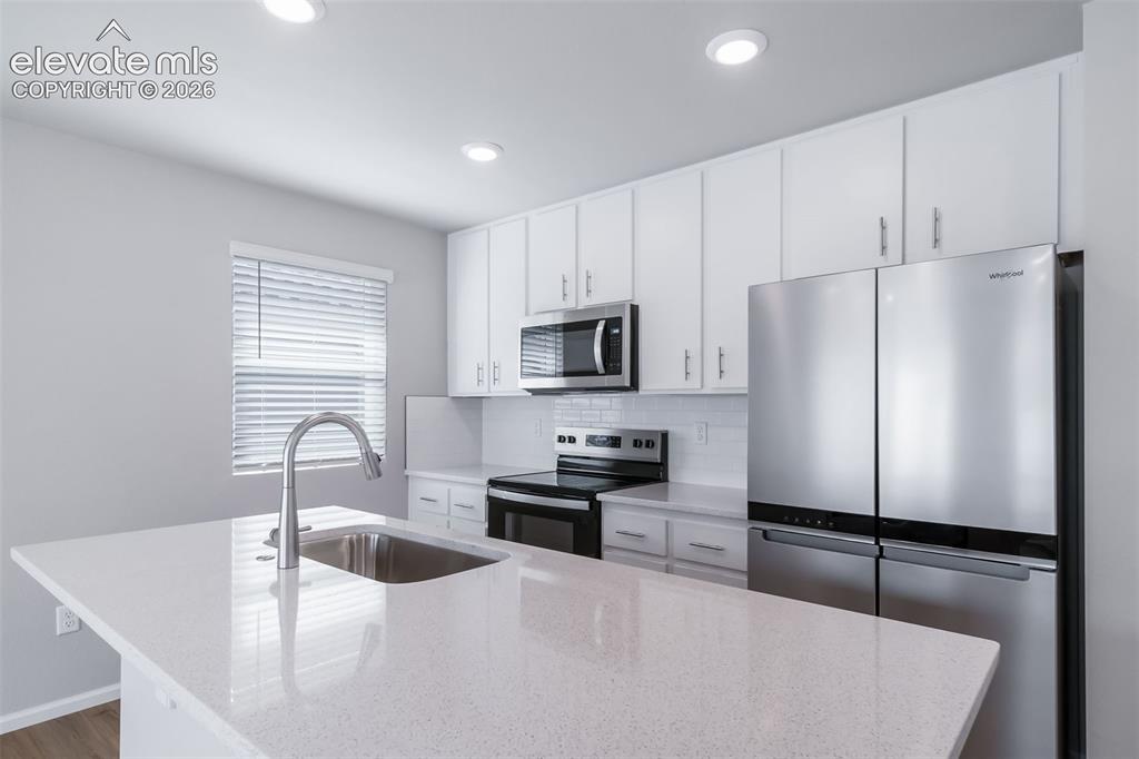 Image 13 of 18: Contemporary kitchen featuring white cabinetry, stainless steel appliances,