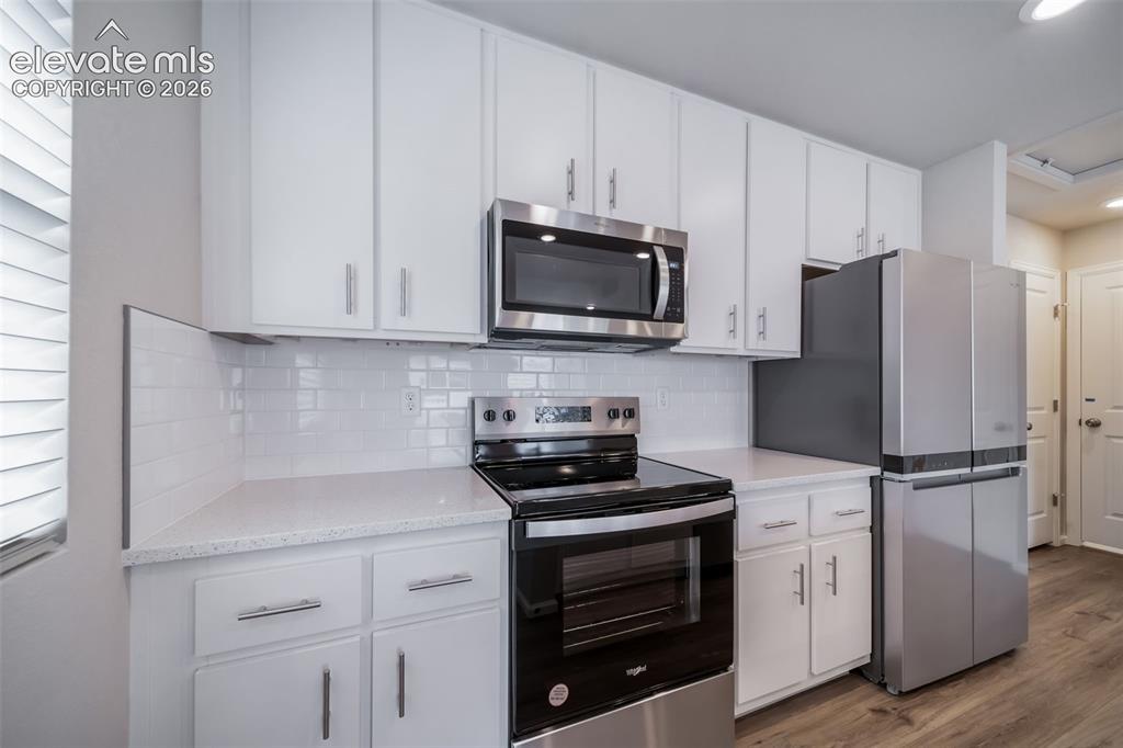 Image 14 of 18: Bright kitchen featuring stainless steel appliances, white subway tile back