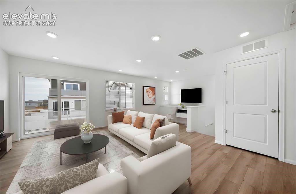 Image 5 of 18: Bright living area featuring wood-finish flooring, recessed lighting, and a