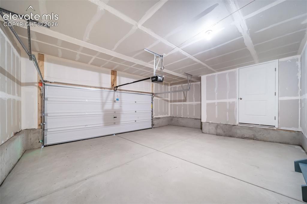 Image 7 of 18: Spacious garage featuring a concrete floor, automatic overhead door, interi