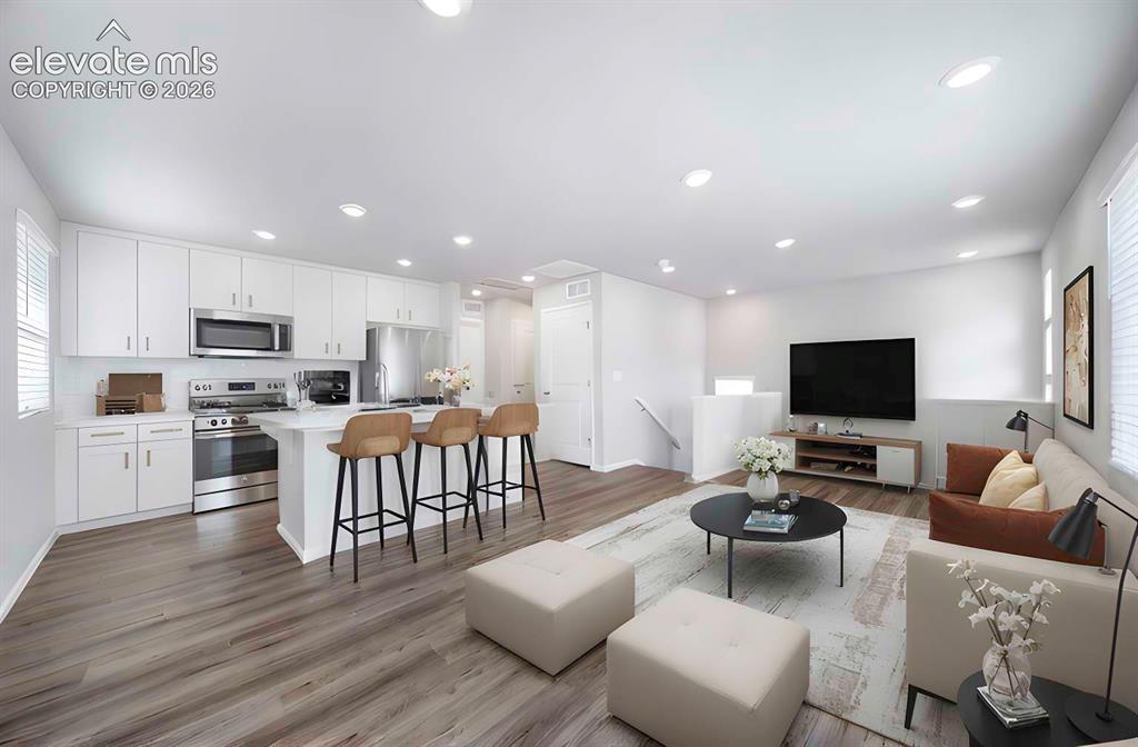Image 8 of 18: Open-concept living space featuring wood-finish flooring, white cabinetry w