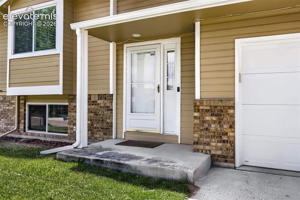 Image 2 of 19: Front entrance featuring a white storm door, partial brick facade, and hori