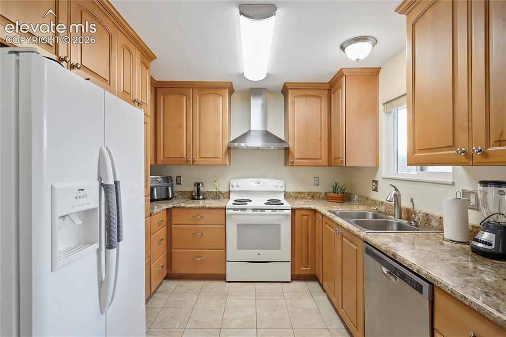 Image 5 of 19: Kitchen featuring light wood cabinetry, stone-finish countertops, and tile