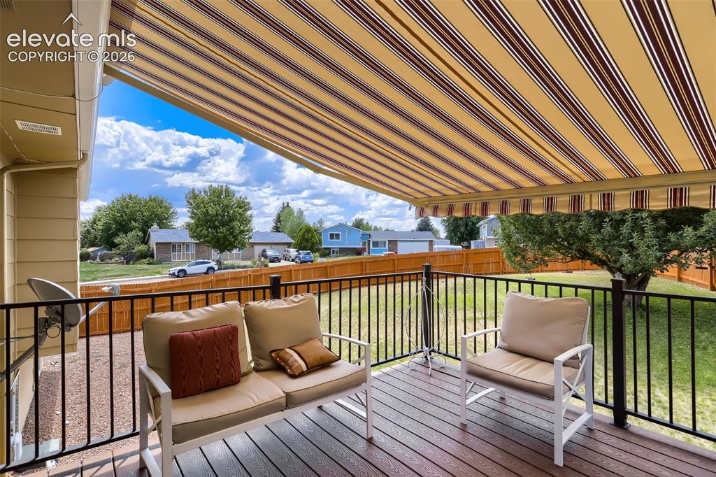 Image 8 of 19: Spacious outdoor deck featuring an extendable striped awning, dark composit