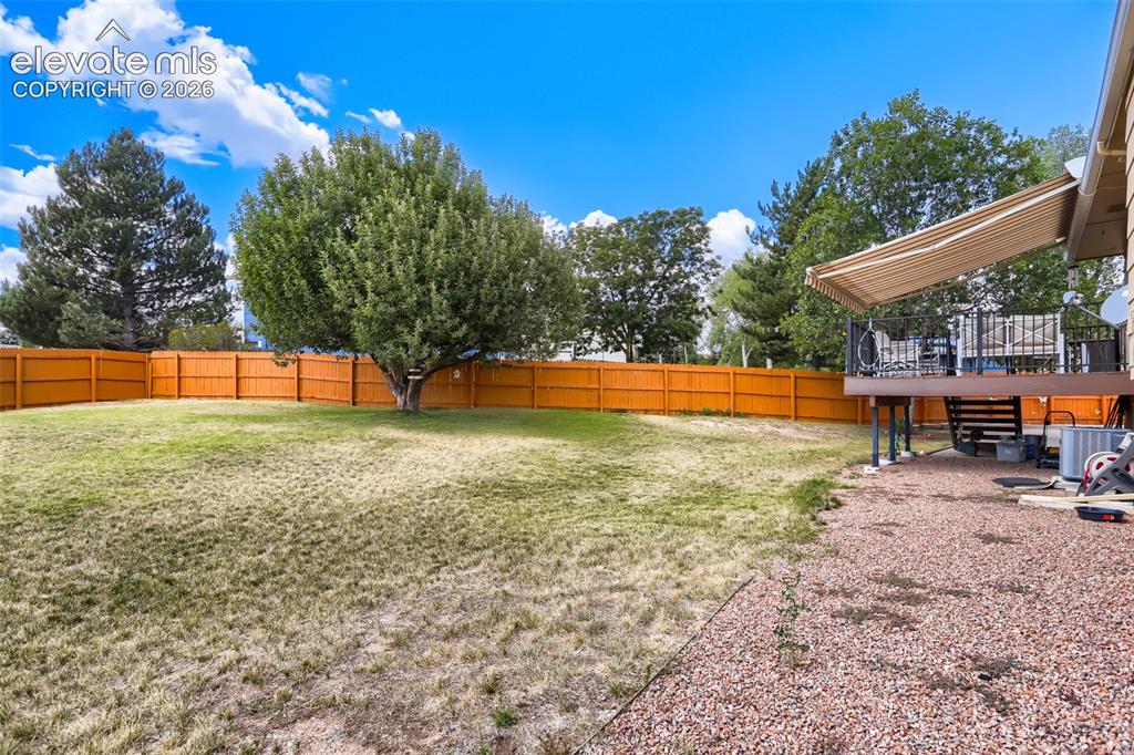 Image 9 of 19: Expansive backyard featuring a wood privacy fence, mature trees, a raised d