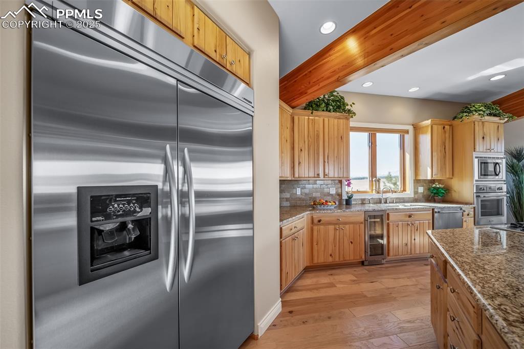 Image 10 of 50: Kitchen featuring built in appliances, light wood-type flooring, tasteful b
