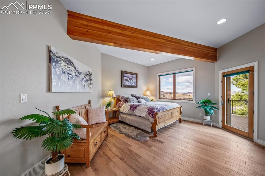 Image 15 of 50: Bedroom with beamed ceiling, wood-type flooring, access to exterior, and re