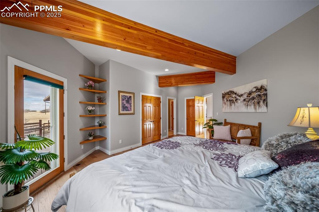 Image 16 of 50: Bedroom with beamed ceiling and light wood-style flooring
