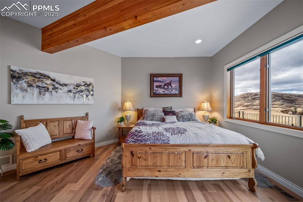 Image 17 of 50: Bedroom featuring beamed ceiling, wood finished floors, a mountain view, an
