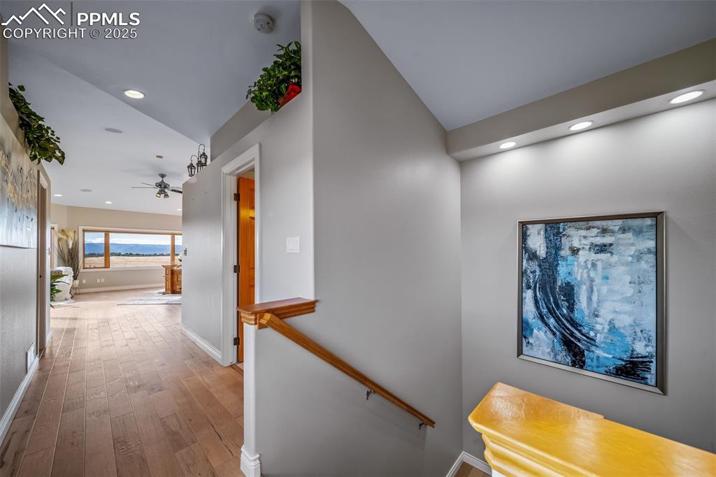Image 20 of 50: Hallway featuring an upstairs landing, wood finished floors, and recessed l