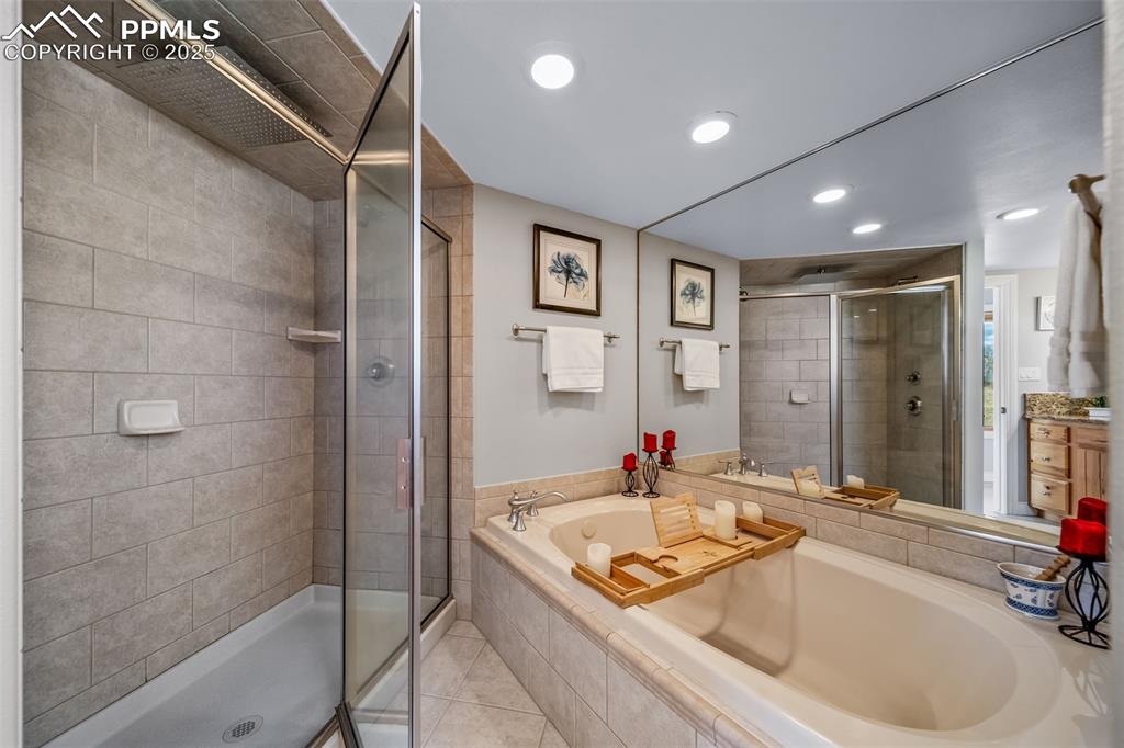 Image 27 of 50: Full bath featuring a shower stall, vanity, a garden tub, light tile patter
