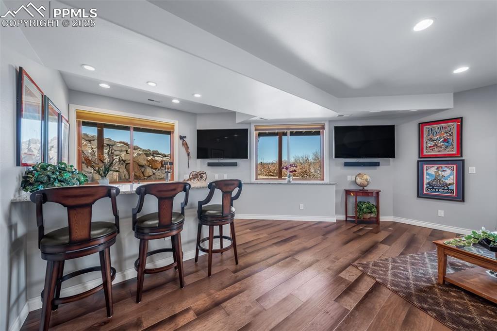 Image 28 of 50: Bar area featuring recessed lighting, dark wood finished floors, and light 