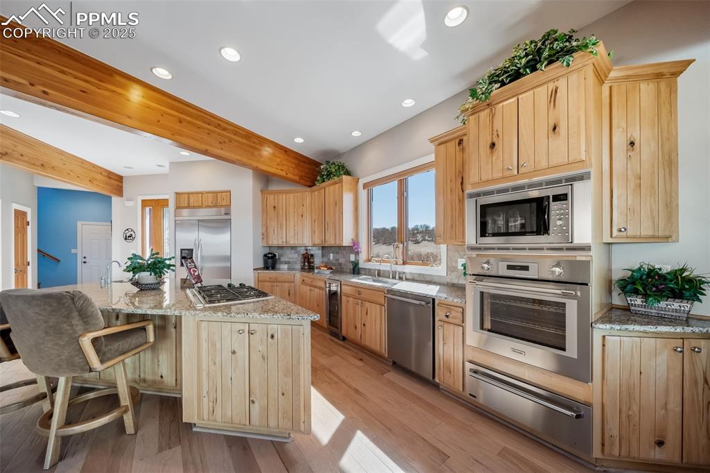Image 9 of 50: Kitchen featuring beamed ceiling, light brown cabinetry, built in appliance
