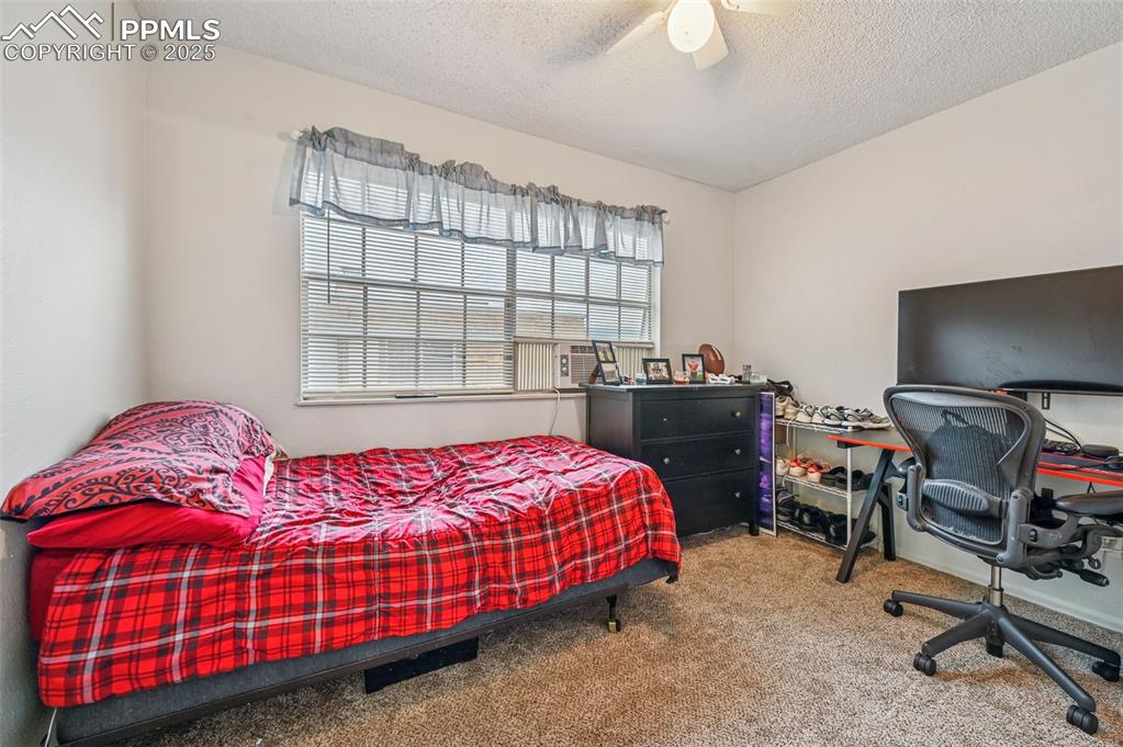 Image 13 of 21: Bedroom featuring carpet, a ceiling fan, a textured ceiling, a desk, and co