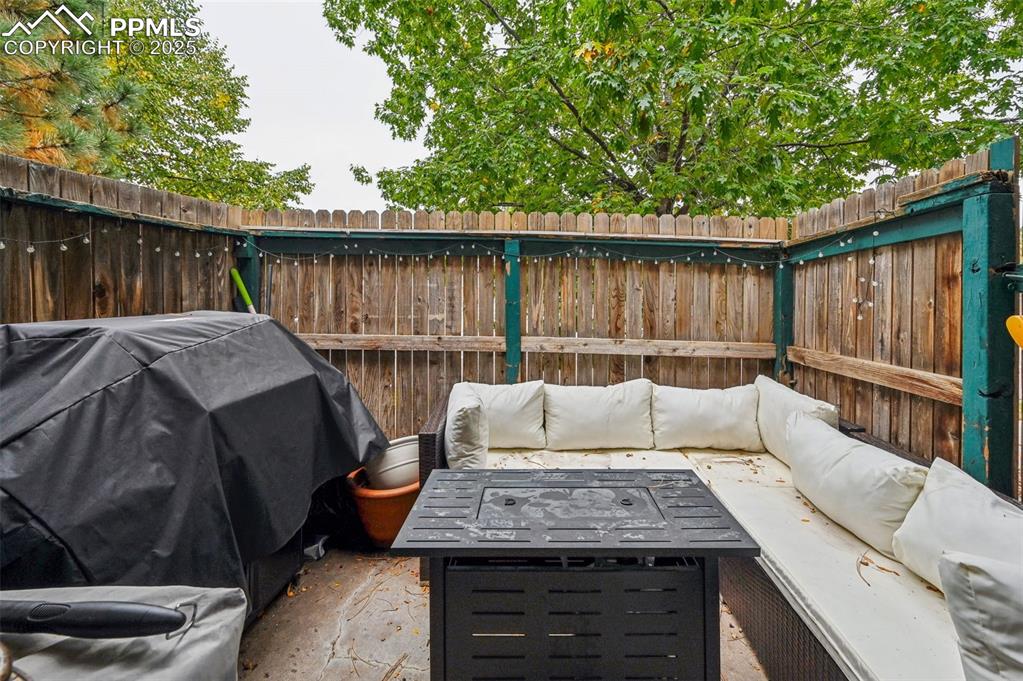 Image 15 of 21: Fenced backyard featuring an outdoor living space with a fire pit and area 