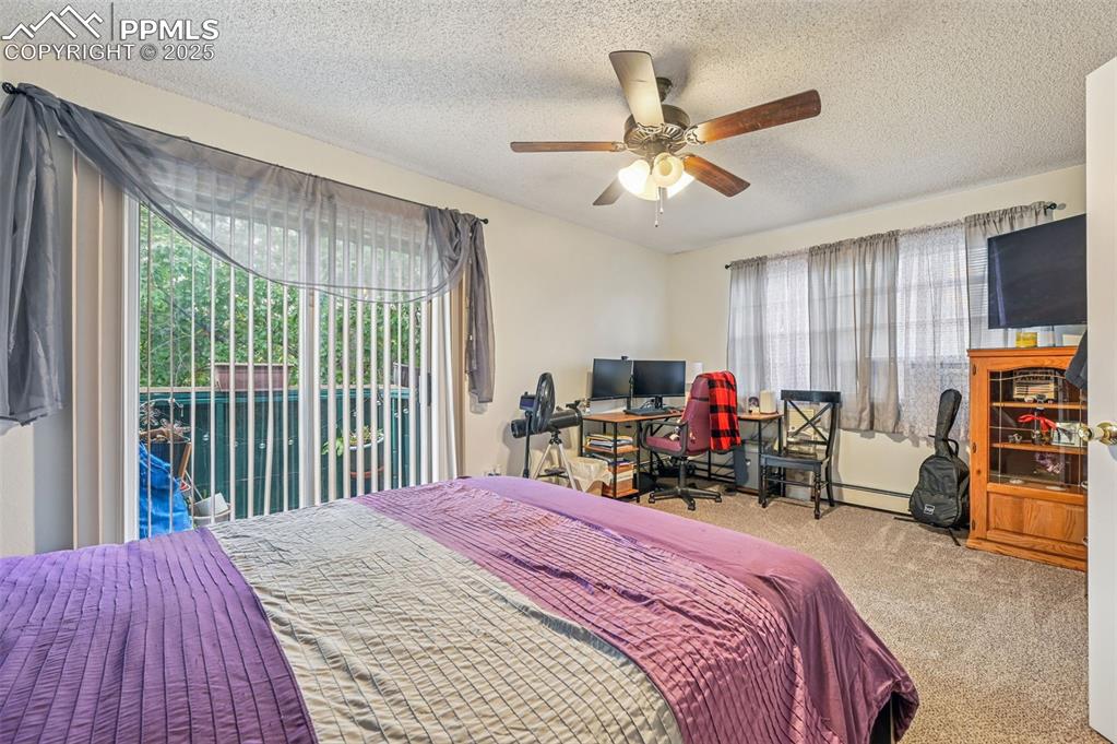 Image 17 of 21: Carpeted bedroom with a textured ceiling, access to exterior, a desk, a cei