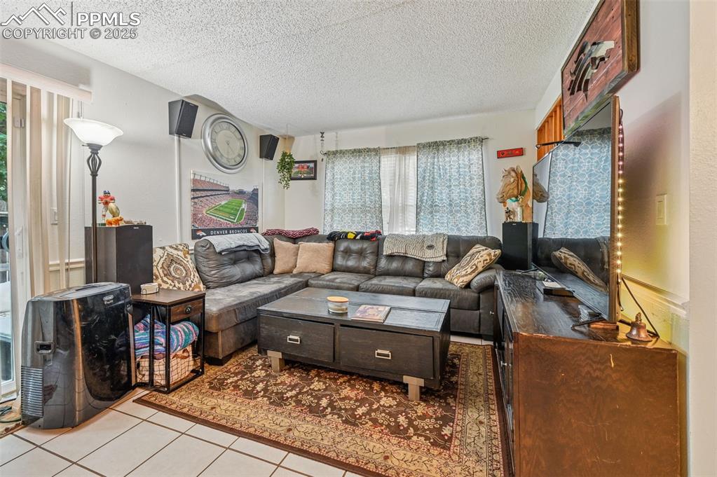 Image 7 of 21: Living room featuring light tile patterned floors and a textured ceiling