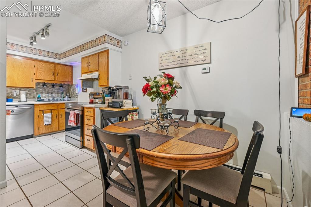 Image 8 of 21: Dining area with light tile patterned floors, a baseboard radiator, a textu