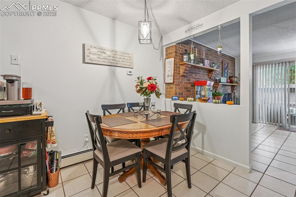 Image 9 of 21: Dining area with a textured ceiling, light tile patterned floors, a baseboa