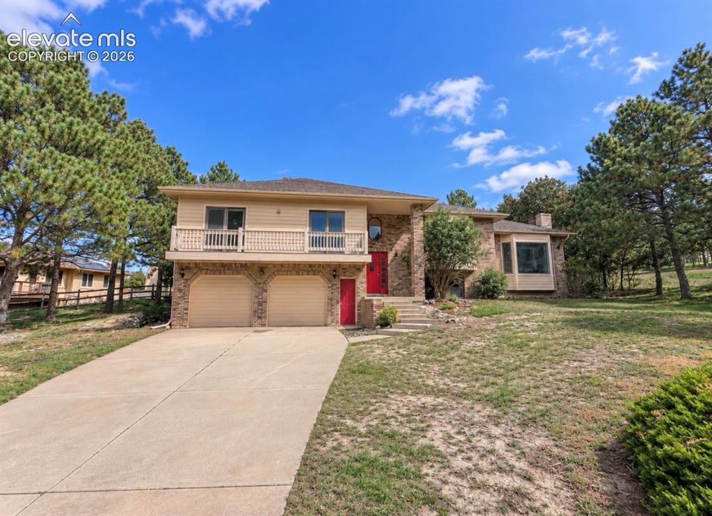 Caption: Split-level residence featuring a two-car garage, brick and siding exterior, a front balcony, a prom