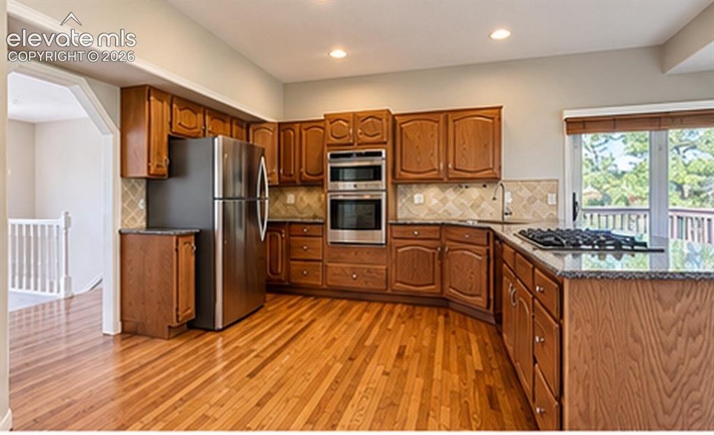 Image 2 of 8: Hardwood flooring, stainless steel appliances, wood cabinetry, stone counte