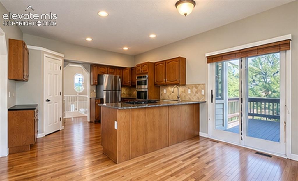 Image 3 of 8: Kitchen with wood-finish flooring, wood cabinetry, stainless steel applianc
