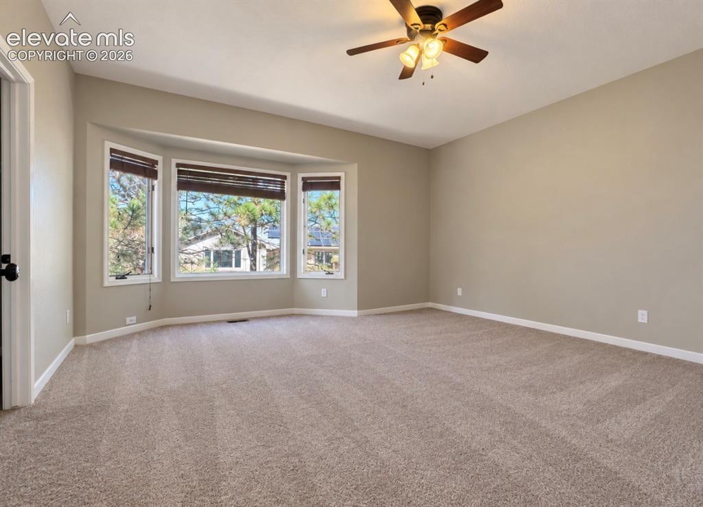 Image 5 of 8: Spacious room featuring a bay window, neutral wall tones, plush carpeting, 