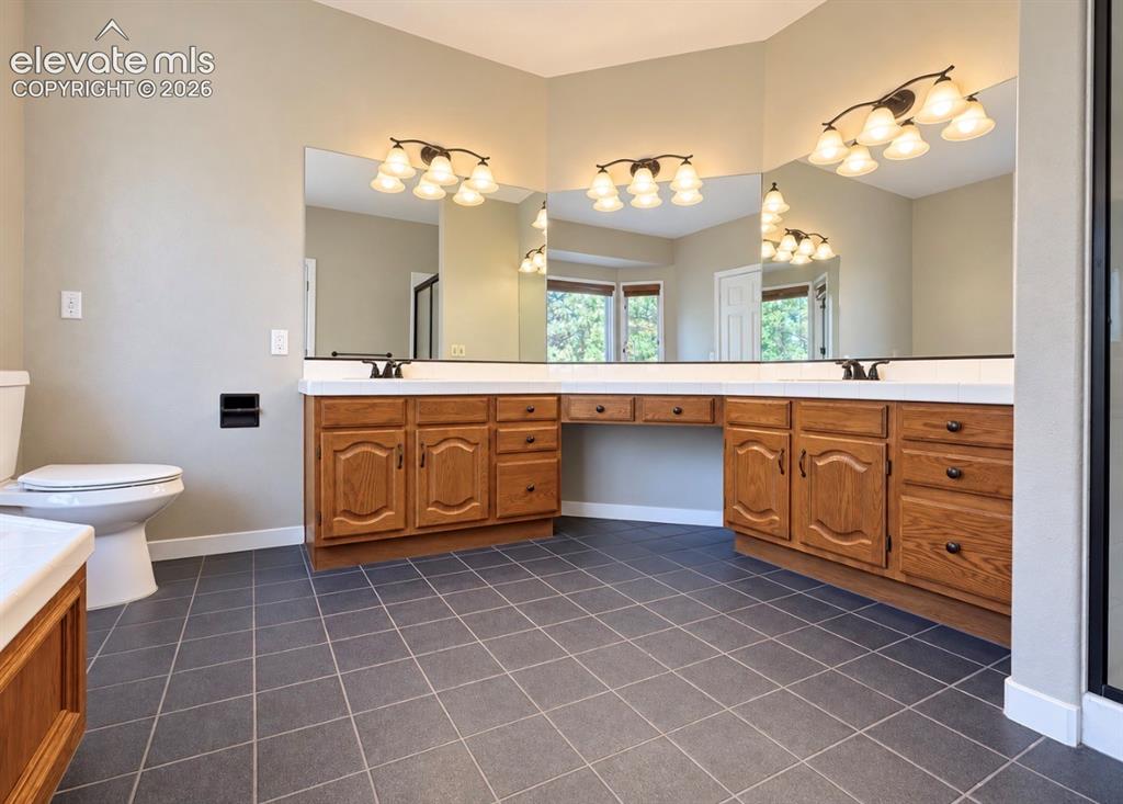 Image 7 of 8: Expansive vanity with wood-finish cabinetry, dual sinks, and an integrated