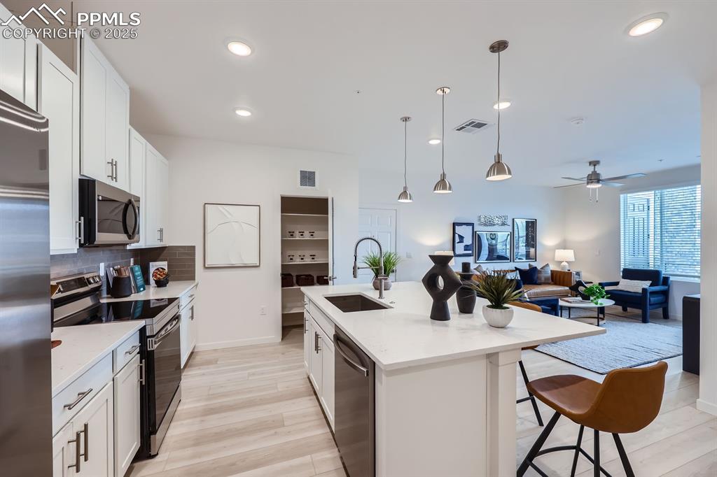 Image 4 of 9: Kitchen with stainless steel appliances, white cabinets, backsplash, decora