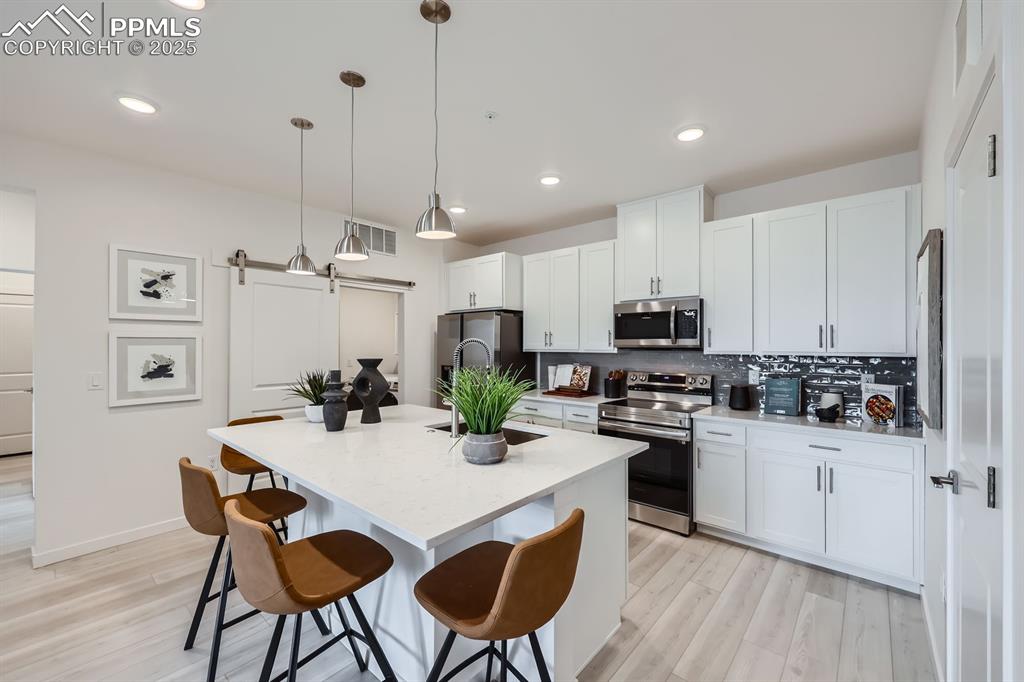 Image 5 of 9: Kitchen featuring a breakfast bar, tasteful backsplash, appliances with sta