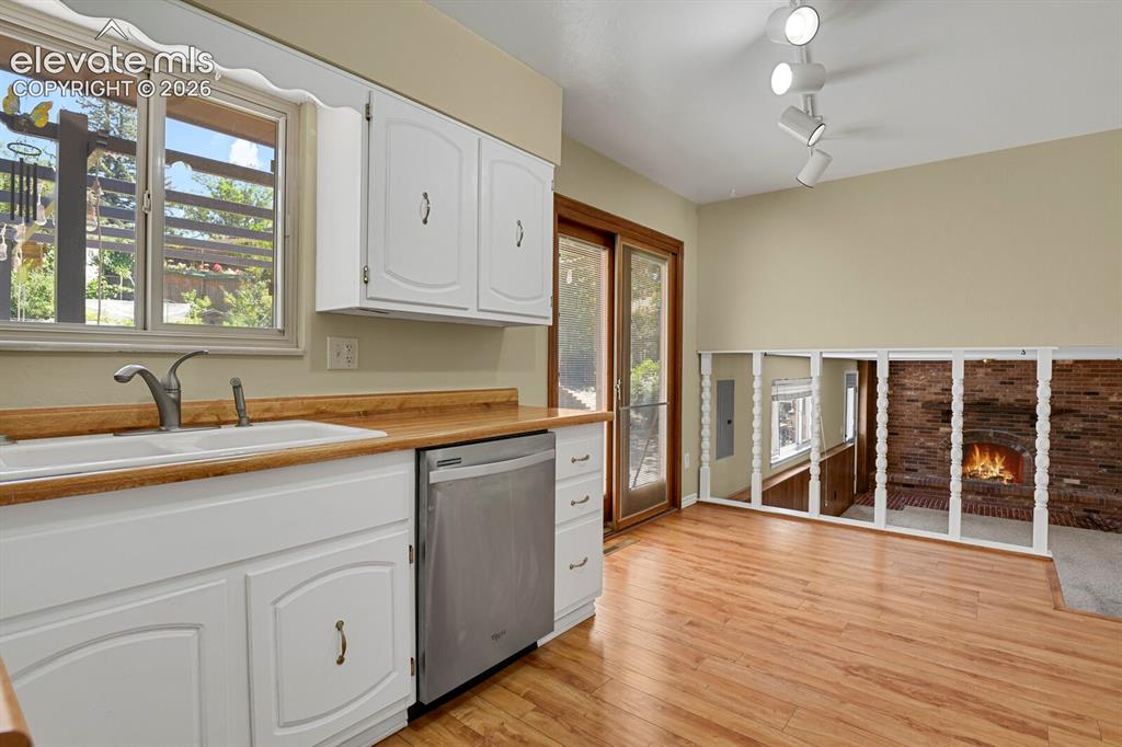 Image 10 of 34: White cabinetry and wood-finish countertops, stainless steel dishwasher, an