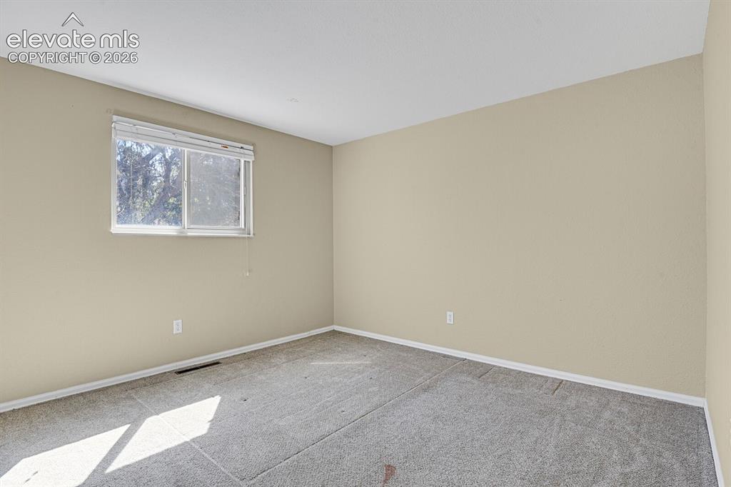 Image 17 of 34: Windowed room with neutral-toned walls, textured ceiling, and gray carpet f