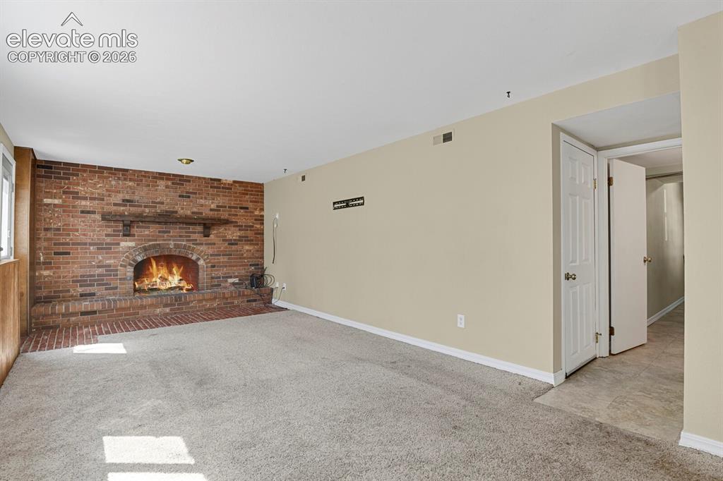 Image 20 of 34: Spacious interior featuring a brick fireplace with a wood mantle, neutral w
