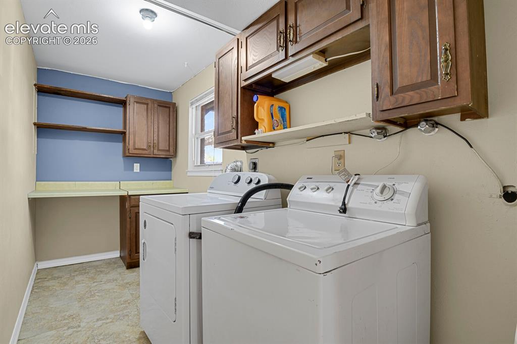 Image 24 of 34: Laundry room featuring vinyl flooring, built-in cabinetry, upper shelving,