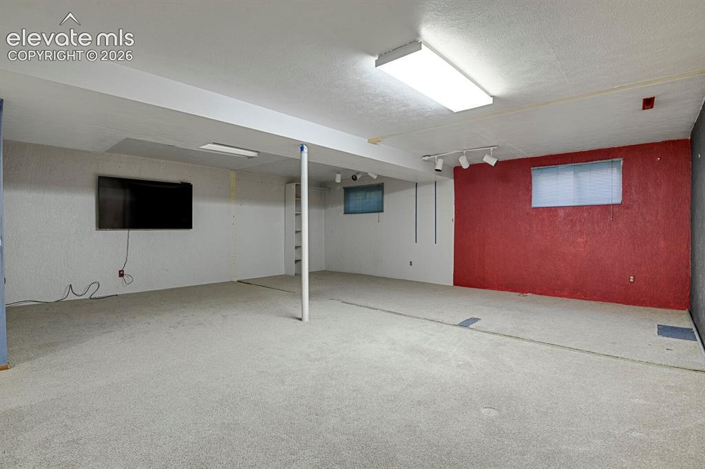 Image 25 of 34: Spacious lower-level room featuring light gray carpeting, white walls, and