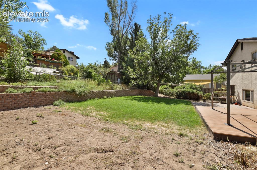Image 28 of 34: Expansive outdoor space featuring a wood-finish deck, a section of manicure