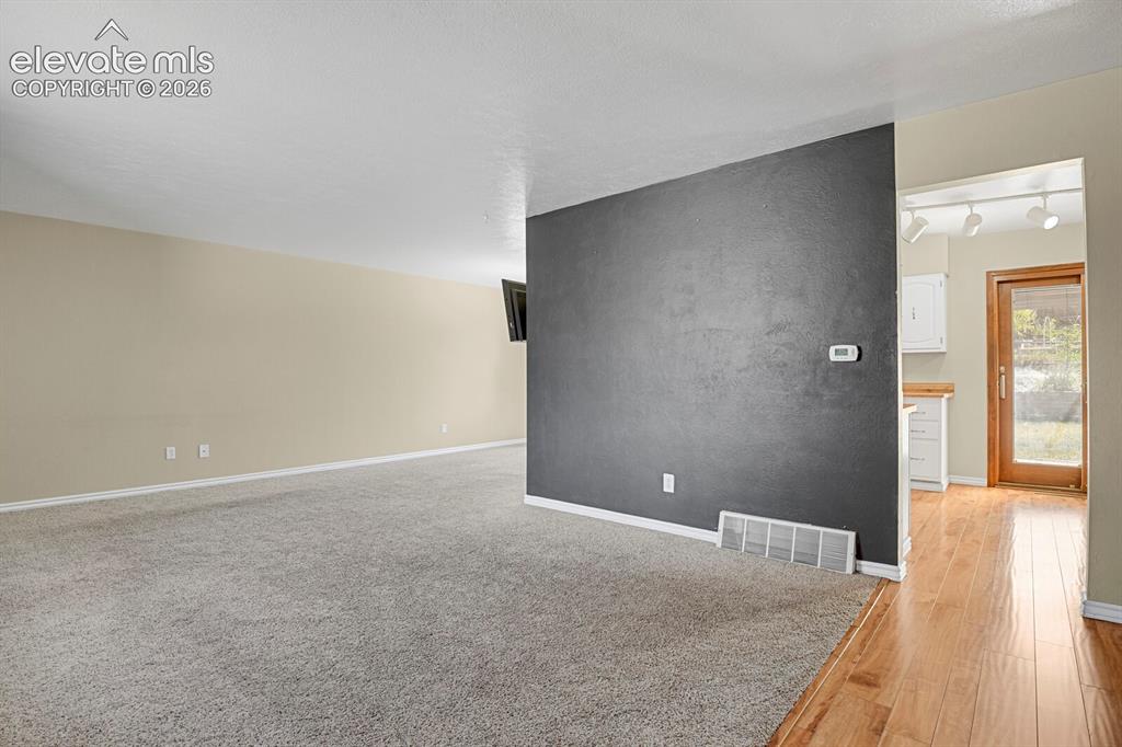 Image 4 of 34: Spacious room with light neutral walls and gray carpeting