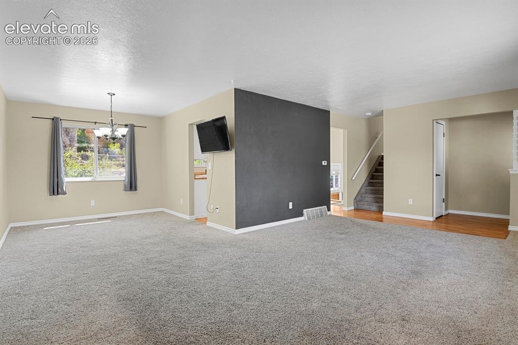 Image 5 of 34: Expansive living area featuring light-colored walls and grey carpeting