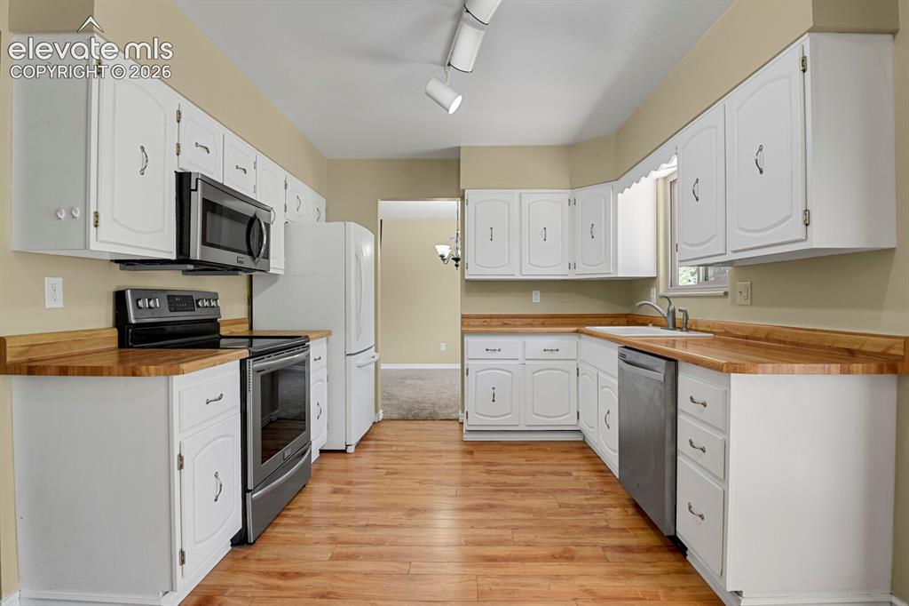 Image 8 of 34: Kitchen featuring white cabinetry, wood-finish countertops, wood-finish flo