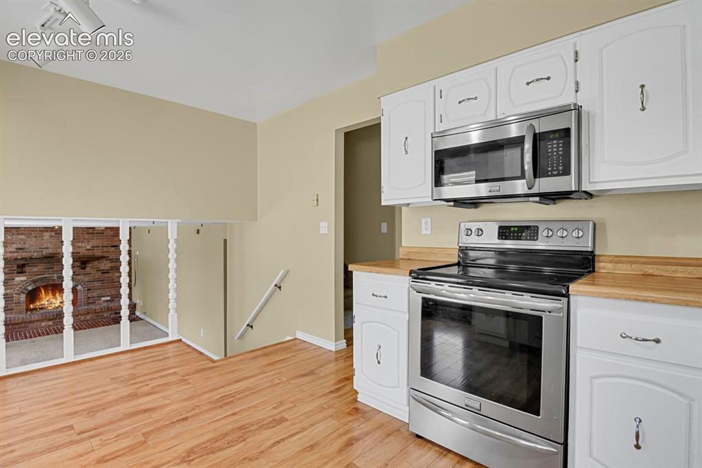 Image 9 of 34: Wood-finish flooring, white cabinetry, stainless steel microwave, stainless