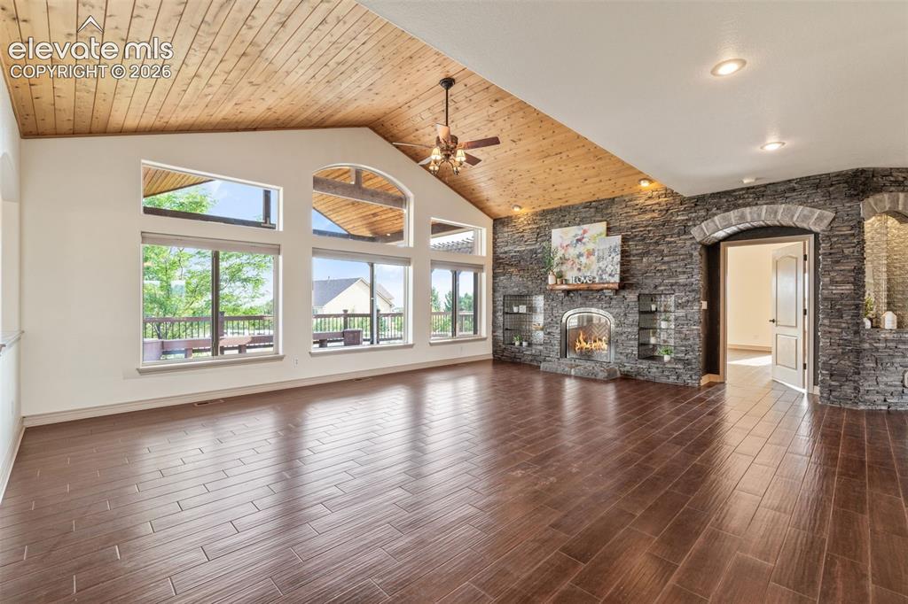 Image 10 of 49: Vaulted wood-paneled ceiling, large picture windows, stone-clad fireplace w