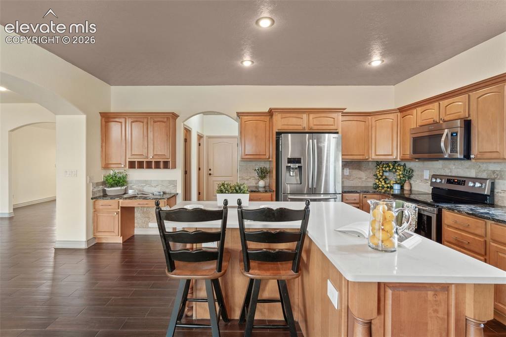 Image 13 of 49: Kitchen featuring wood-finish cabinetry, stainless steel appliances, a larg