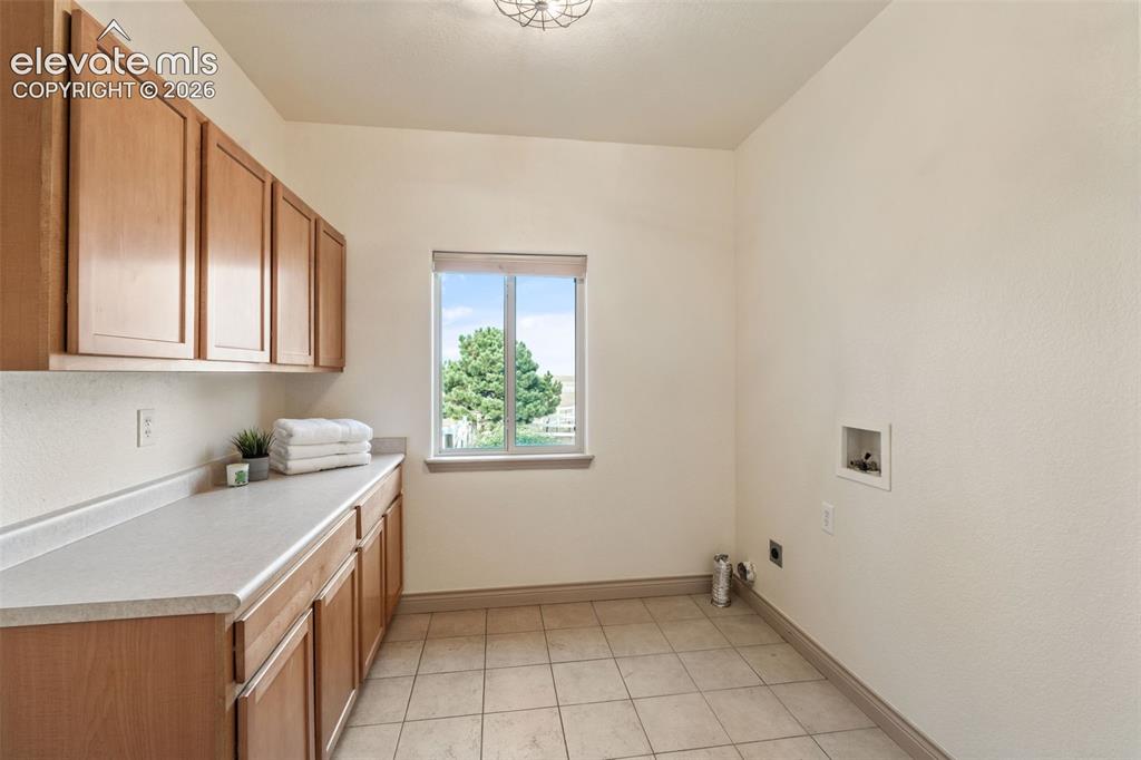 Image 19 of 49: Tiled flooring, upper and lower cabinetry, light-toned countertop, and an e