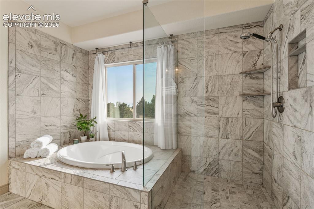 Image 27 of 49: Walk-in shower with glass enclosure, built-in shelving, and a rain shower h