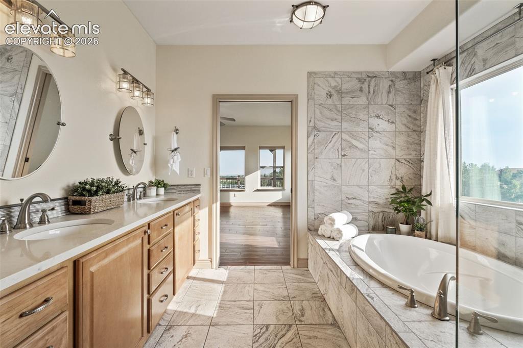 Image 28 of 49: Dual vanity with undermount sinks, a freestanding soaking tub, and a large