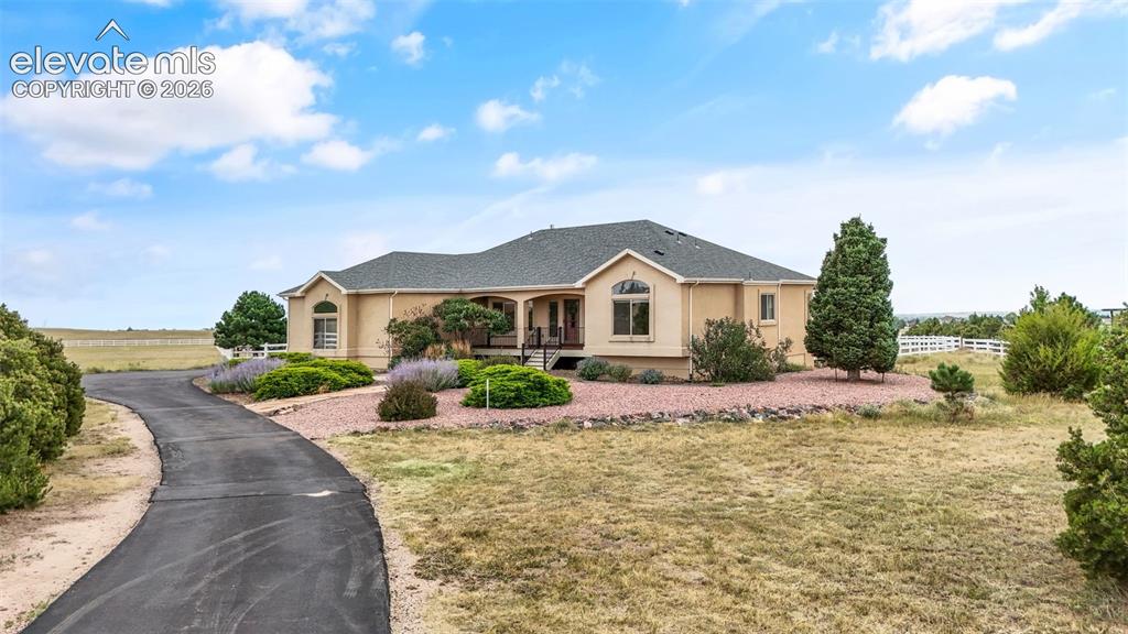 Image 3 of 49: Spacious ranch-style residence featuring a paved driveway, stucco exterior,