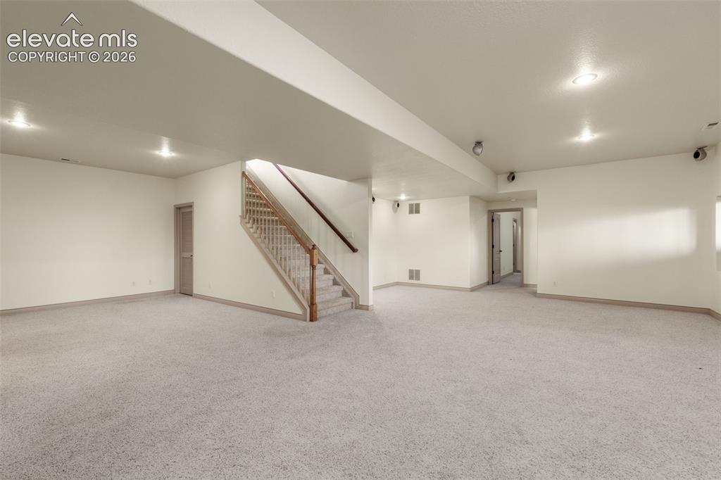 Image 34 of 49: Expansive room featuring light-colored carpeting, recessed lighting, a wood