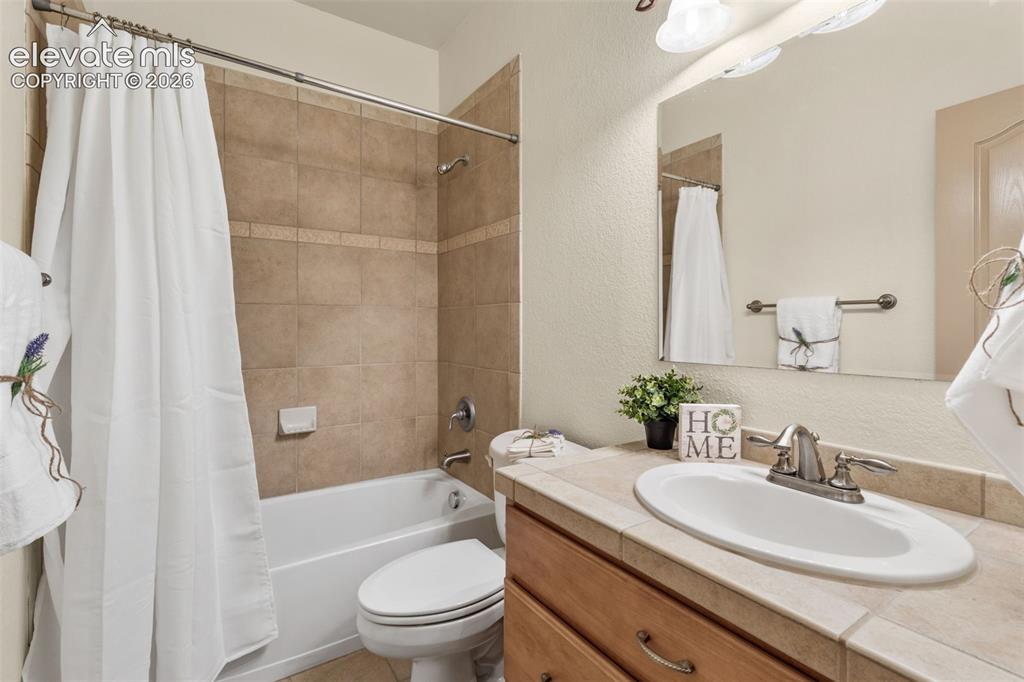Image 35 of 49: Built-in vanity with wood-finish cabinetry, tile countertop, and undermount