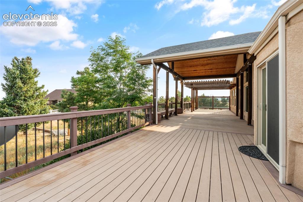 Image 37 of 49: Expansive outdoor deck with composite decking, a wood-slatted covered patio